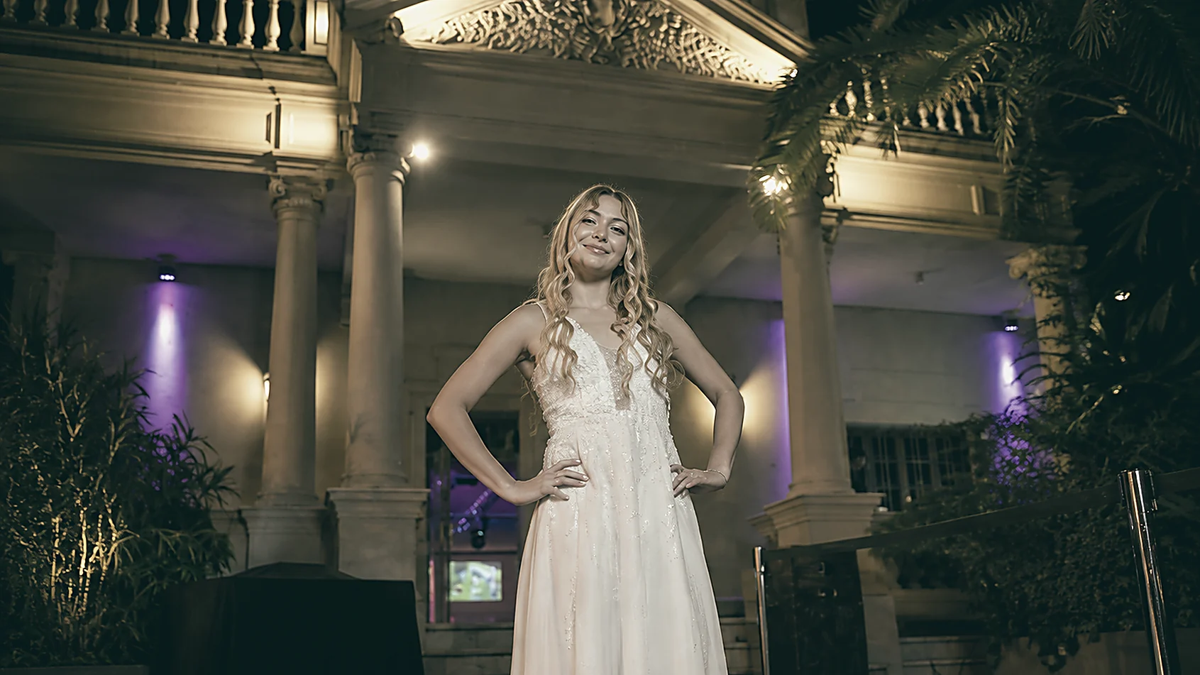 Mujer posando en la entrada iluminada de una casona, alfombra roja