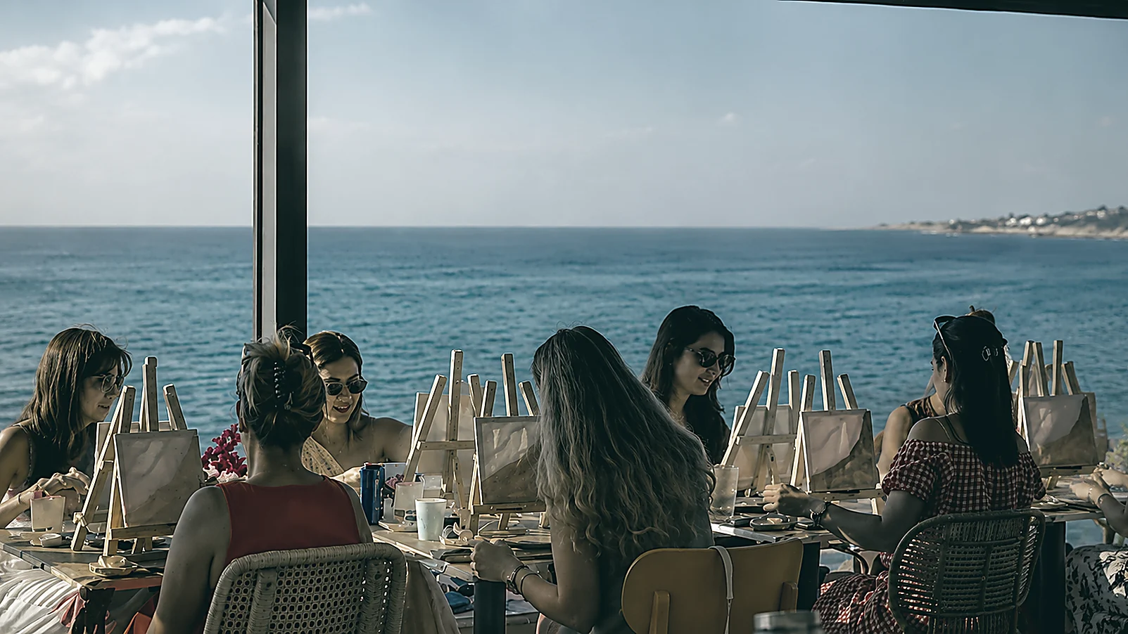 Grupo pintando en caballetes frente al mar, durante un workshop creativo